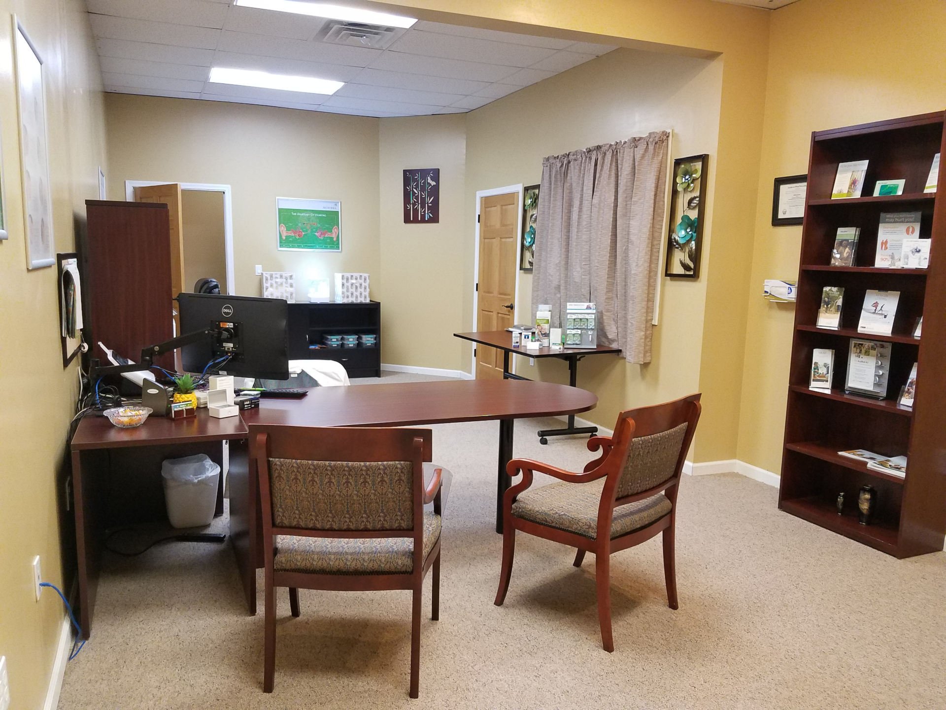 technician office with desk as well as displays with hearing aid brochures and accessories