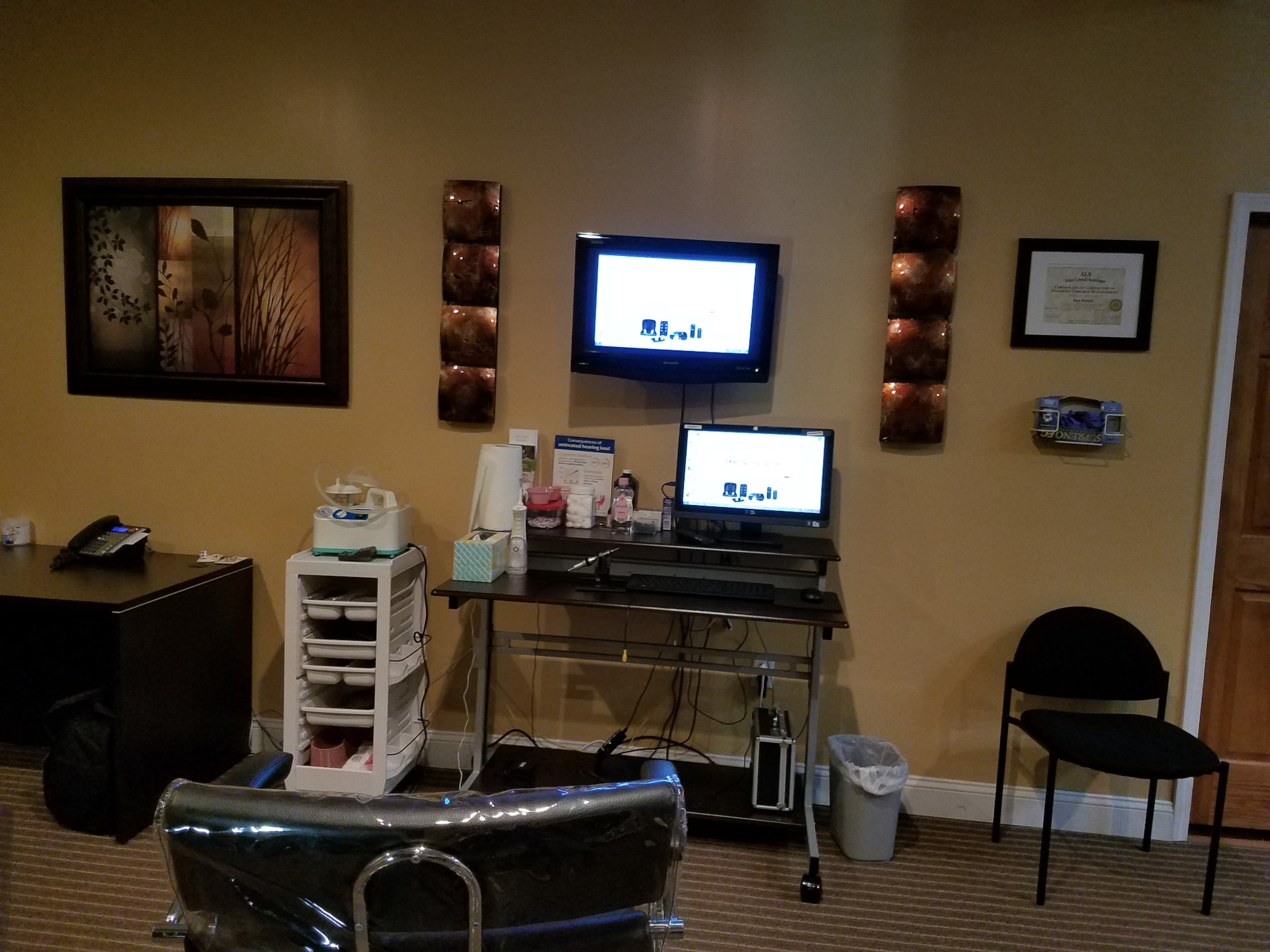 wax removal room with chair and table with monitors on back wall