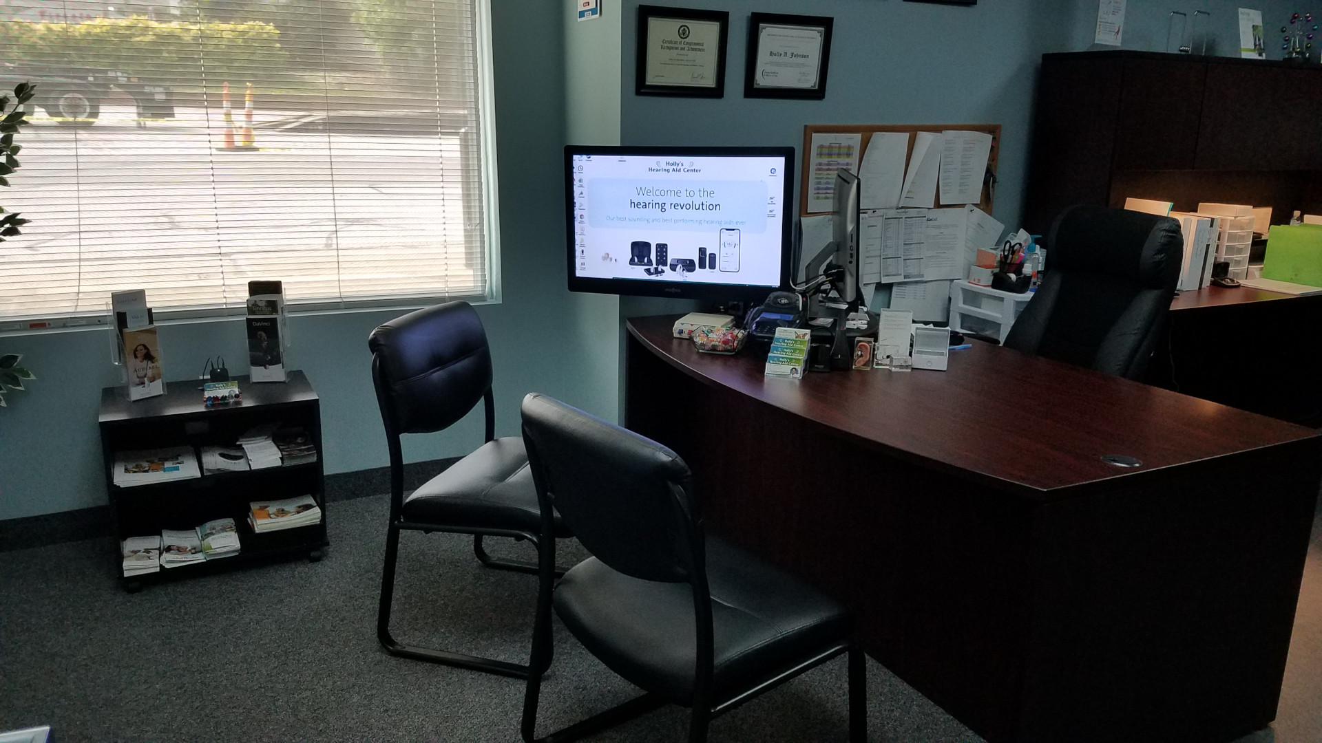 desk in hearing specialist office with monitor and chairs