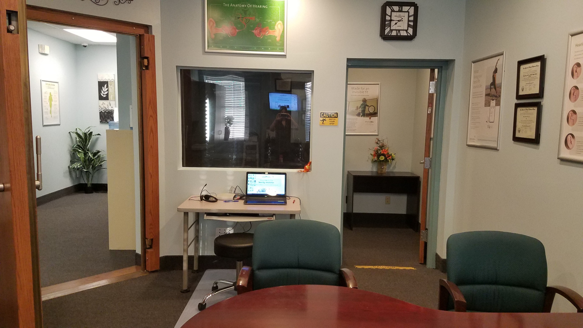 outside hearing test room in hearing specialist office with table and computer by window