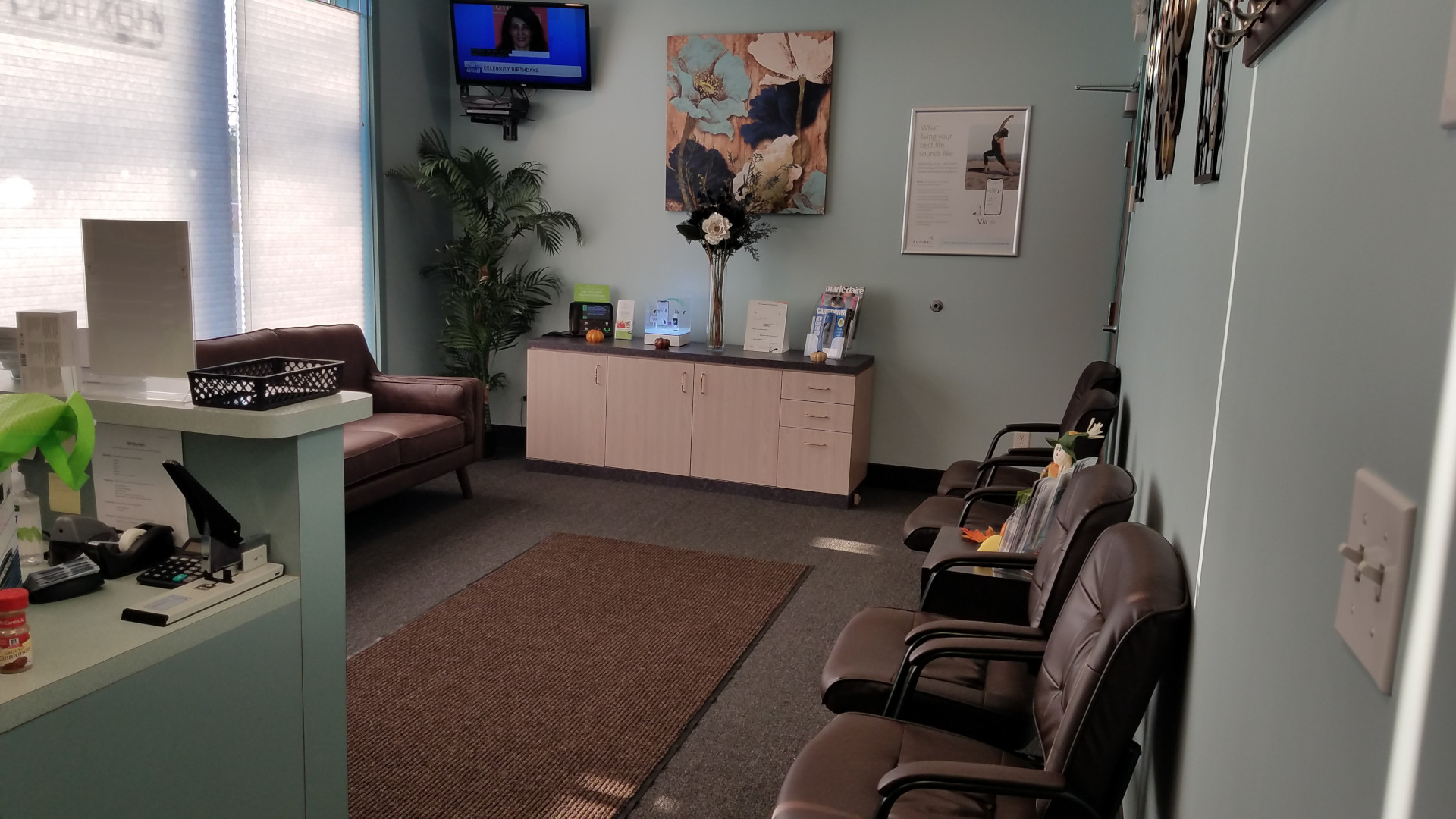 waiting room with small display on back wall along with chairs and tv